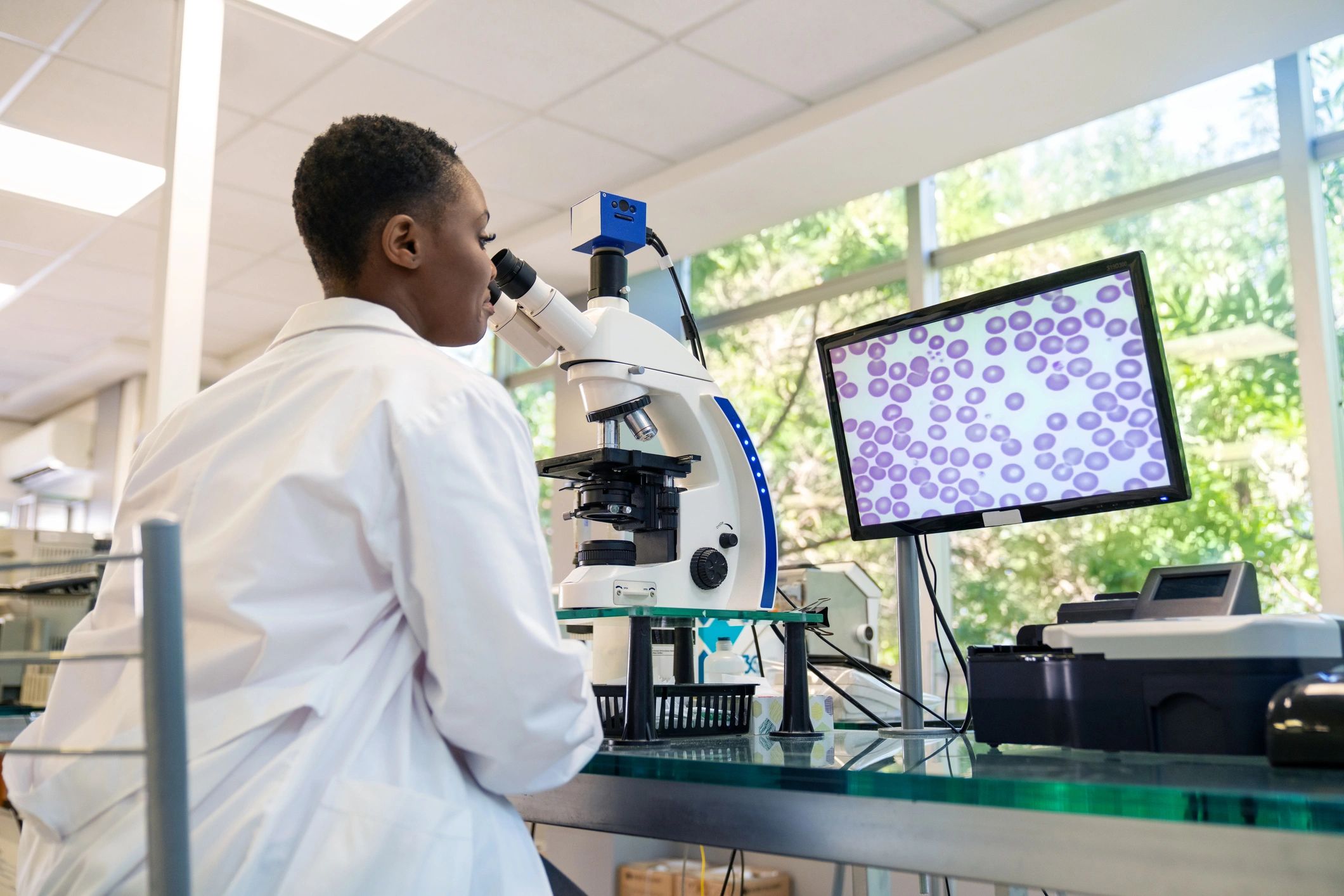 Laboratory technician using a microscope to analyze a sample